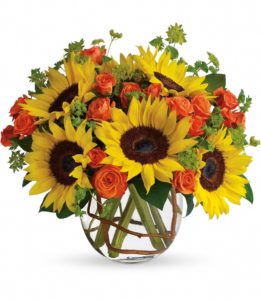 Gorgeous yellow and orange bouquet of roses and sunflowers in bubbly glass vase