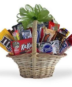 Snack gift basket stuffed with candy and topped with ribbon bow