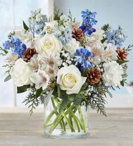 White roses, blue delphinium, pine cones and alstromeria are the perfect combination for a winter table setting.