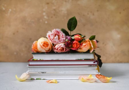 Books with fragrant garden roses on a table and beautiful background